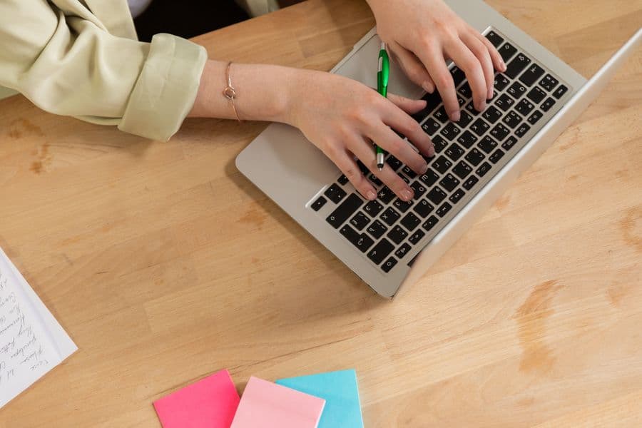 Typing on a laptop next to colourful sticky notes